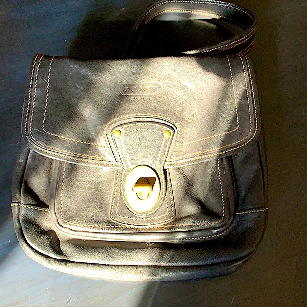 A large black leather Coach crossbody bag with the satin striped inside